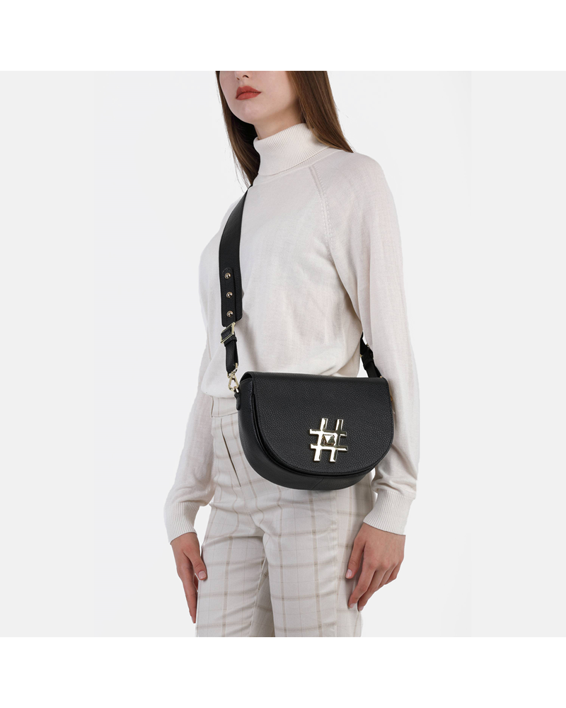 Modelka z małą torebką listonoszką crossbody ze skóry w kolorze klasycznej czerni z biżuteryjną aplikacją hashtag