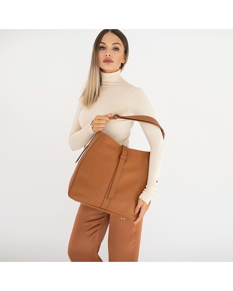 Modelka w  casualowym białobrązowym stroju z jasnobrązową dużą torebką skórzaną worek