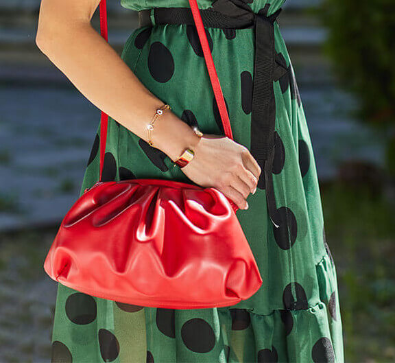 Modelka z czerwoną torebką typu worek w zielonej sukience